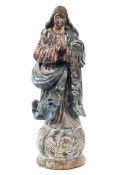 A carved wooden religious figure, modelled standing with hands clasped in prayer,