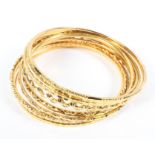 A collection of 10 full hoop bangles of variable styles and designs,