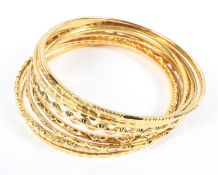 A collection of 10 full hoop bangles of variable styles and designs,