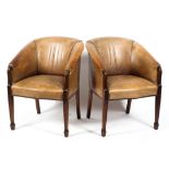 Two brown leather style studded tub armchairs, on reeded tapering legs,