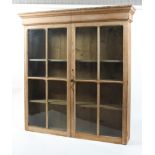 A large late 19th century glazed pine bookcase, the double doors enclosing three adjustable shelves,