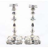 A pair of sterling silver Georgian style candlesticks on square loaded bases.