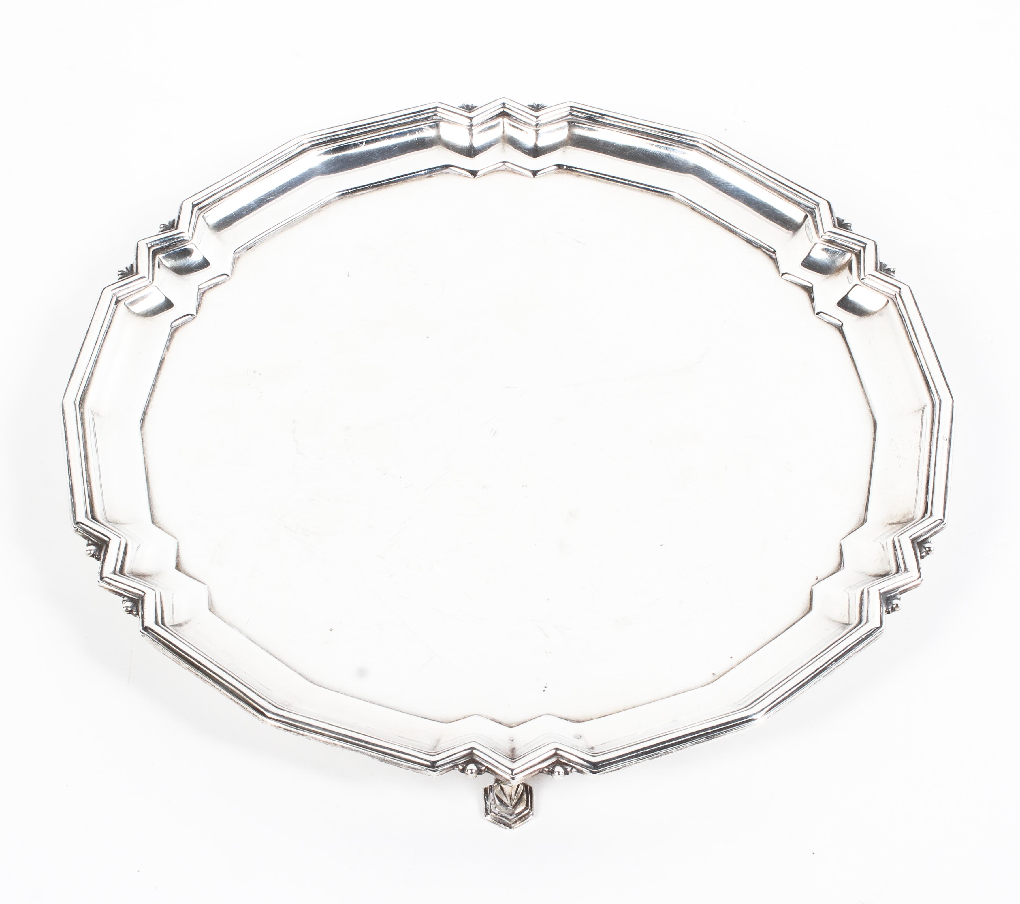 A sterling silver circular card tray or salver with geometric pie crust border raised on three feet