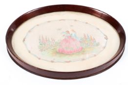 An Edwardian mahogany oval tray inset with silk embroidered picture of Watteauesque figures in a