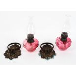 A pair of Victorian gilt-metal mounted cranberry glass wall mounted oil lamps,