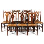 A set of seven oak Arts and Crafts dining chairs, with pierced heart-shaped splats and rush seats,