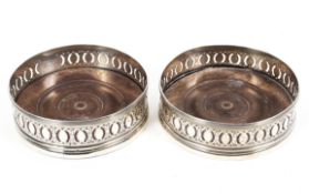 A pair of Georgian sterling silver wine bottle coasters with turned wooden bases, London,
