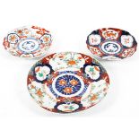 Three Japanese Imari pattern dishes, each painted with panels of flowers and animals,