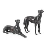 Two bronze models of greyhounds, both wearing collars, one standing, the other lying down,