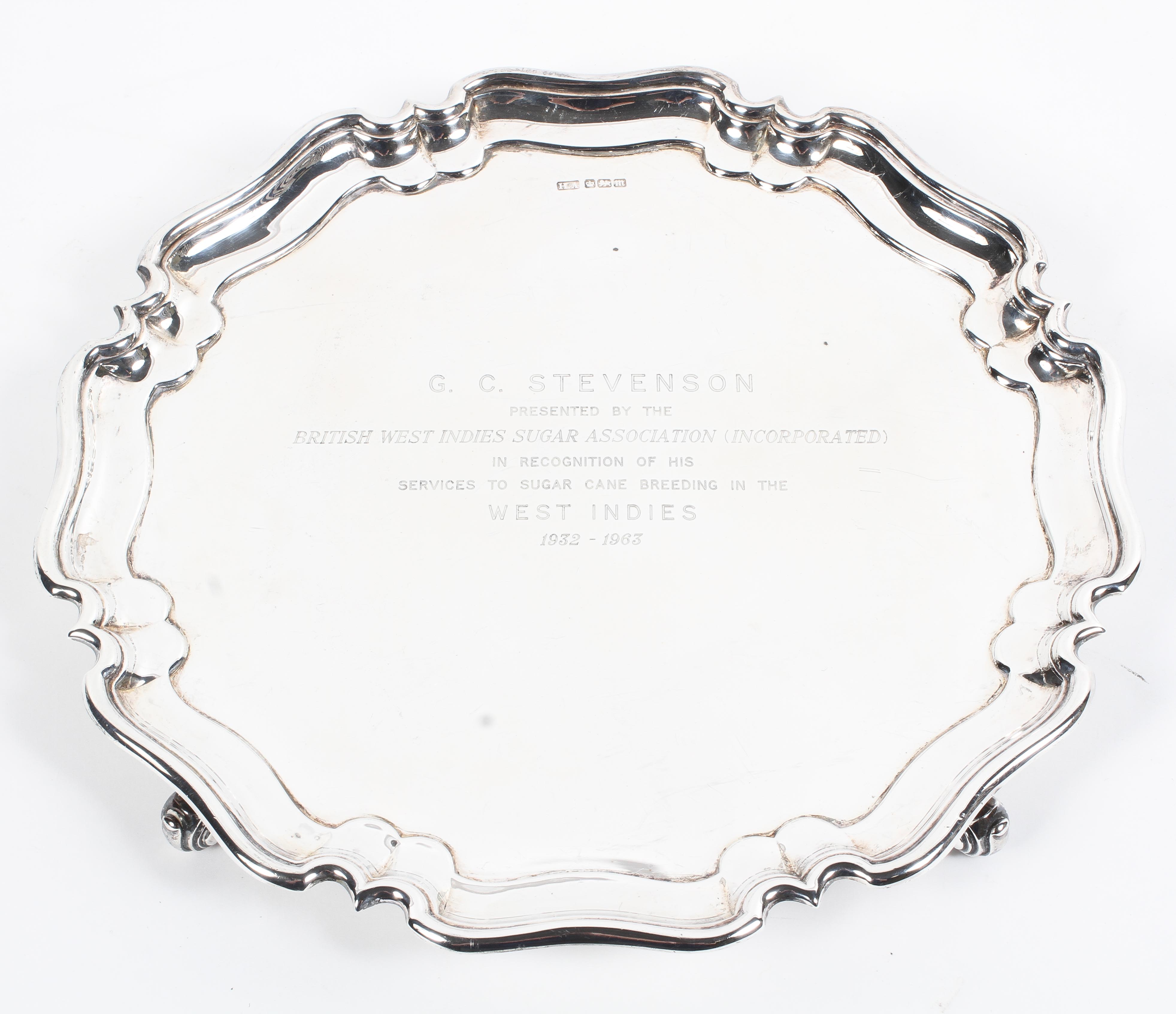 A sterling silver salver or card tray with pie crust border raised on three scrolling feet by Atkin