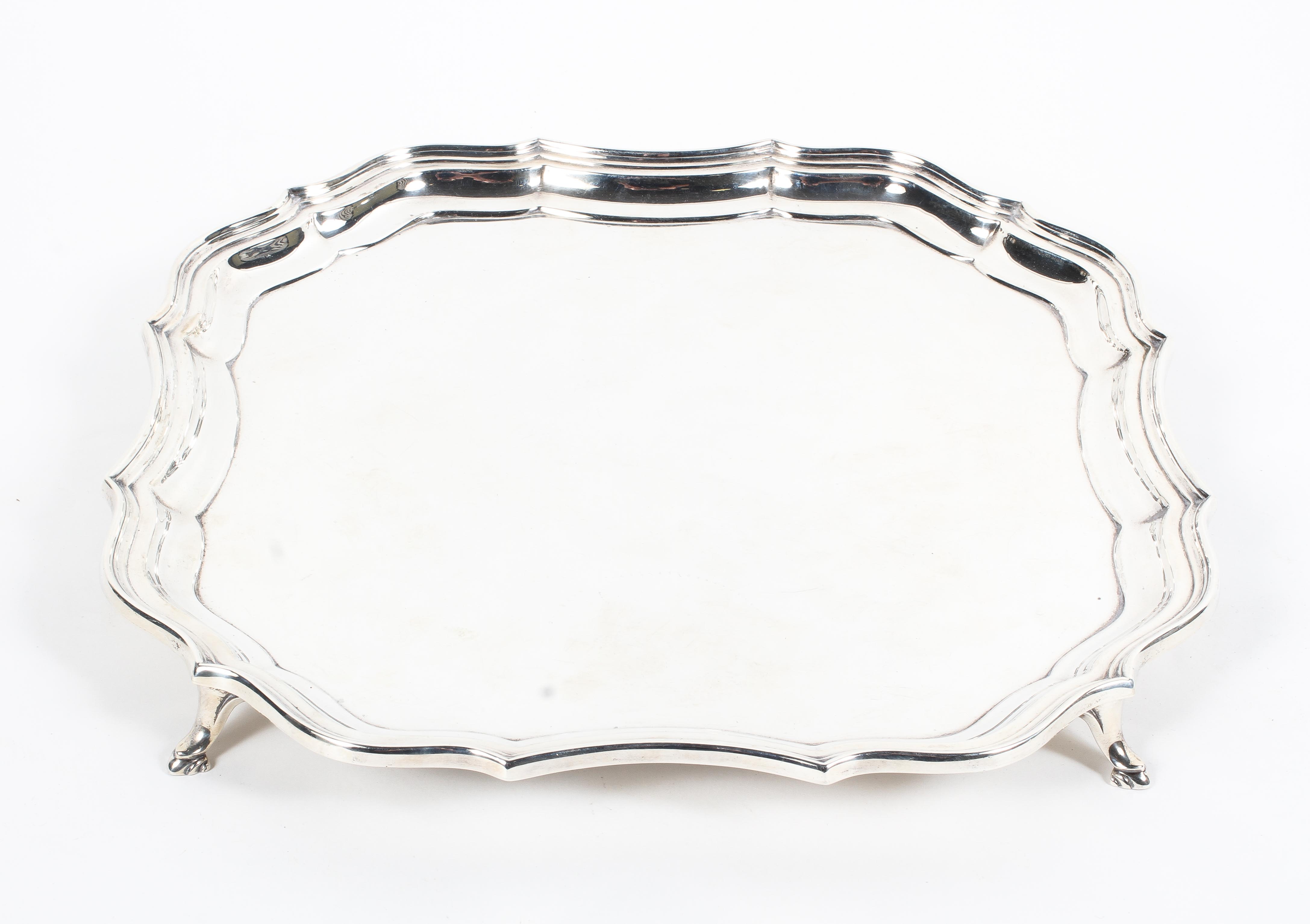 A sterling silver salver or card tray of square form with gadrooned border raised on four feet.