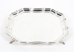A sterling silver salver or card tray of square form with gadrooned border raised on four feet.