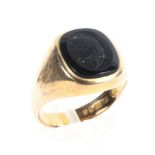 A yellow metal signet ring set with a cushion shaped embossed seal onyx.