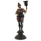A 19th century spelter figural candlestick, cast as a standing soldier holding a foliate nozzle,