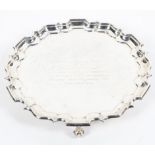 A sterling silver circular salver or card tray with pie crust border raised on three scrolling feet.