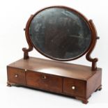 A Georgian mahogany dressing table swing mirror, the oval cushion framed mirror above three drawers,