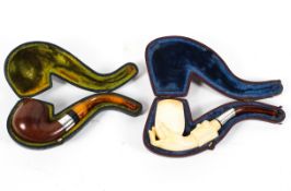 A carved meerschaum pipe and a wooden example, the first carved with a hand holding the bowl, cased,