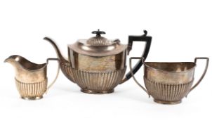 A three piece sterling silver tea set with half fluted design and ebonised handle and knop by