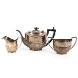 A three piece sterling silver tea set with half fluted design and ebonised handle and knop by