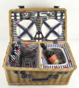 A wicker hamper, fitted with cutlery, cups, plates and a corkscrew,