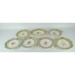 Six Victorian Rococo style plates and a serving platter, all with scrolling edges,