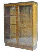 A veneered walnut display cabinet, twin doors with inset glass panels, key present, missing shelves,