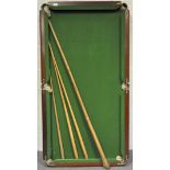 A mahogany framed table top snooker table with three cues,