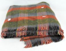 A Scottish woolen tartan blanket, green and red in colour,