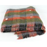 A Scottish woolen tartan blanket, green and red in colour,