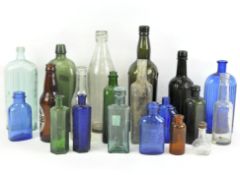 A collection of vintage glass bottles, blue, red, green and white glass examples,