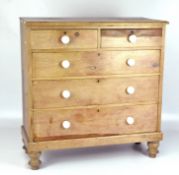 A Victorian stripped pine chest of drawers with white ceramic pull handles,