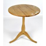 A 20th century small round pine table on a tripod base.