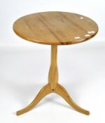 A 20th century small round pine table on a tripod base.