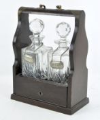 A vintage two bottle tantalus, containing two cut glass decanters, one with brandy decanter label,