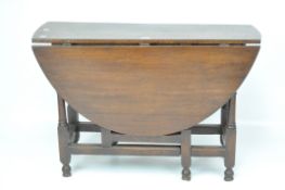 An early 20th century oak oval gate leg table on turned and squared supports,