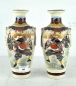 A pair of early 20th century Japanese ceramic vases, each decorated with Samurai and floral motifs,