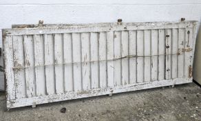Two large wooden vintage shutters, painted white with metal bindings,
