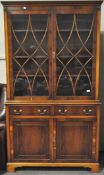 A yew veneered bookcase cabinet, the top with shaped cornice over two astragal glazed doors,