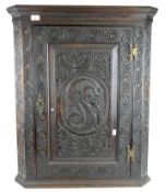 A carved front oak corner cupboard, with hinged door,