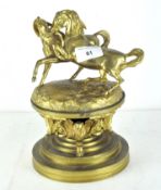 A late 19th/early 20th century gilt brass inkwell, the top adorned with two stylised horses,
