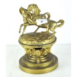 A late 19th/early 20th century gilt brass inkwell, the top adorned with two stylised horses,