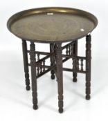 A Middle Eastern brass topped coffee table, with engraved details to the top,