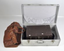 A vintage metal storage case, opening to reveal a leather case and more,