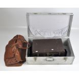 A vintage metal storage case, opening to reveal a leather case and more,