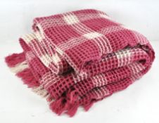 A waffle Welsh blanket, made of 100% wool, pink and white in colour,