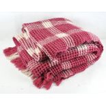 A waffle Welsh blanket, made of 100% wool, pink and white in colour,