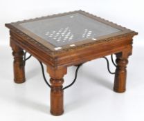 A glass topped hardwood coffee table, of square form, with carved foliate decoration,