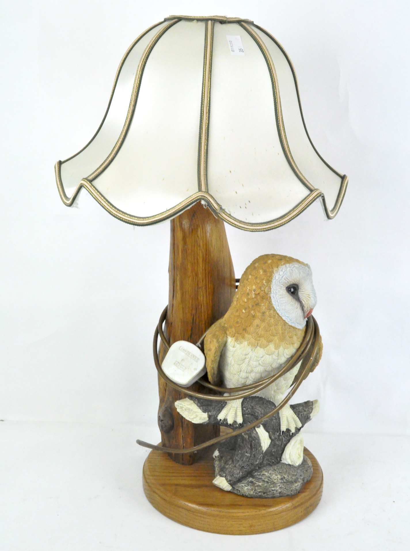 A turned and carved oak lamp base set with a resin figure of a barn owl on a branch, with shade,