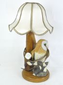 A turned and carved oak lamp base set with a resin figure of a barn owl on a branch, with shade,