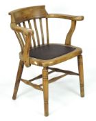 An early 20th century elm/beech captains chair, raised upon turned supports,